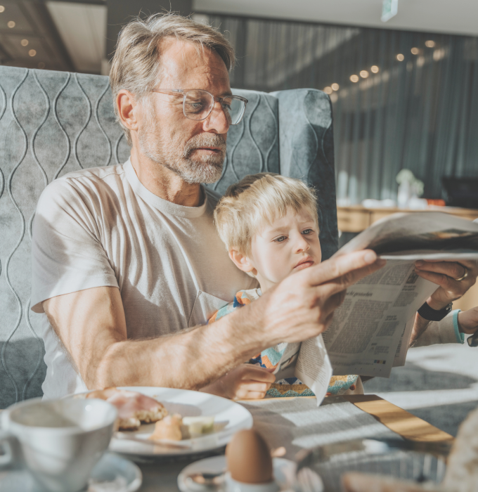 Father and son having breakfast in the hotel restaurant with a newspaper