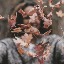 Frau mit Blätterwirbel im Herbst