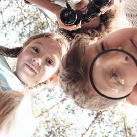Kinder erkunden neugierig die Natur mit Lupe und Fernglas – ein Moment voller Entdeckerfreude beim Familienurlaub in der Hochkönig-Region rund um Maria Alm.