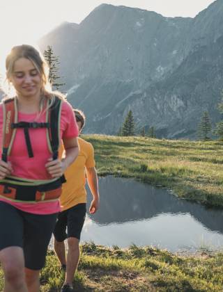 Couple hiking in the mountains on alpine meadows in the sunshine in the Hochkönig region