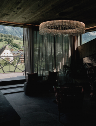 Dunkles Foto des Spa Bereichs mit einer großen Declenlampe mit Kristallen und Ausblick auf die Kirche