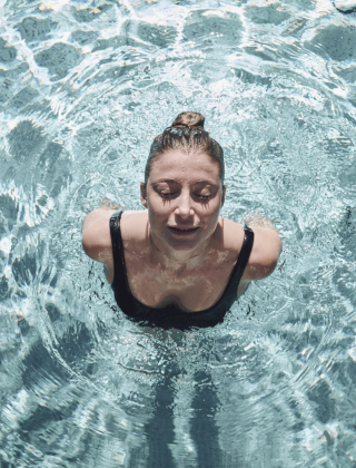 Frau mit geschlossenen Augen beim auftauchen im Pool