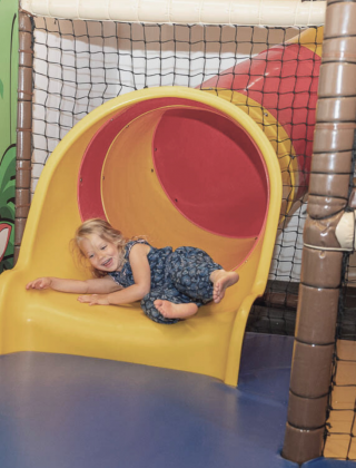 Child sliding through the colorful tube slide in the FUN ARENA at Hotel die HOCHKÖNIGIN, Maria Alm – indoor playground fun in the Salzburg Alps