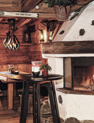 Dengl Alm in Maria Alm mit offenem Holzofenfeuer, rustikalen Holzbänken und Tischen im alpinen Flair des Salzburger Landes