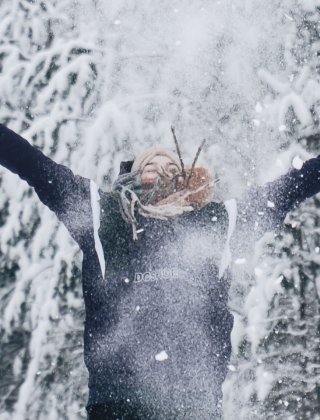 Woman joyfully throwing snow into the air, enjoying the winter magic at Hochkönig.