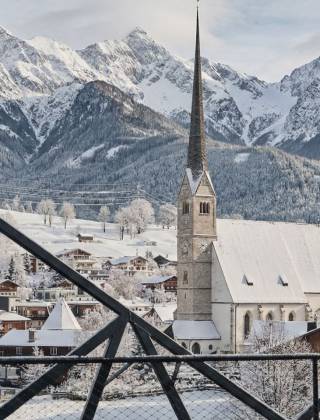 Winterlicher Ausblick vom Hotel die HOCHKÖNIGIN auf die Pfarrkirche Maria Alm mit verschneitem Bergdorf und imposantem Hochkönig-Massiv im Hintergrund – Winterurlaub, Bergurlaub, Salzburger Land, Österreich
