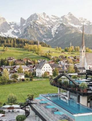 Infinitypool im TIARA SPA des Wellnesshotels die HOCHKÖNIGIN in Maria Alm mit Blick auf die Kirche und das Hochkönig-Gebirge.
