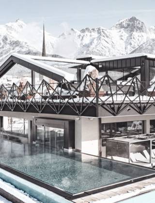 Infinity pool at the TIARA SPA of Hotel die HOCHKÖNIGIN in Maria Alm am Hochkönig with panoramic views of the snow-covered mountains of Salzburger Land, Austria.