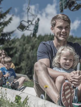 Familie beim Rutschen im Waldrutschenpark am Prinzenberg Natrun in Maria Alm