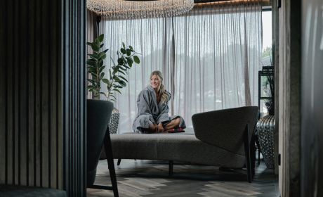 Frau sitzend, lachend auf einer Liege im Ruhebereich des SPA