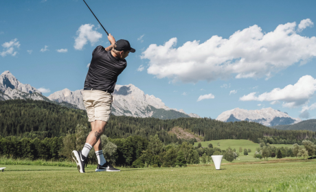 Golfers teeing off on the golf course with a view of the mountains