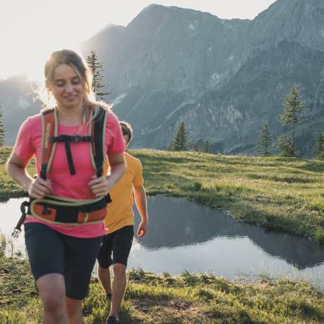Couple hiking in the mountains on alpine meadows in the sunshine in the Hochkönig region