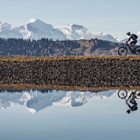 Fahrradfahrer am see mit schneebedeckten Bergen im Hintergrund
