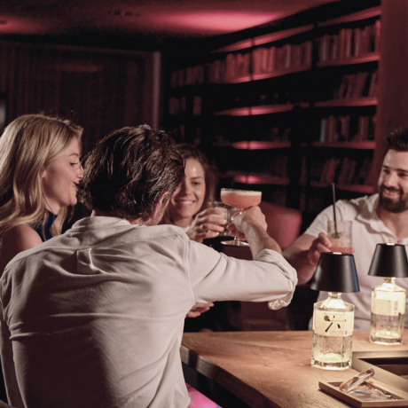 Two couples sitting with cocktails in the HIGH QUEEN BAR at the Hotel die HOCHKÖNIGIN in Maria Alm