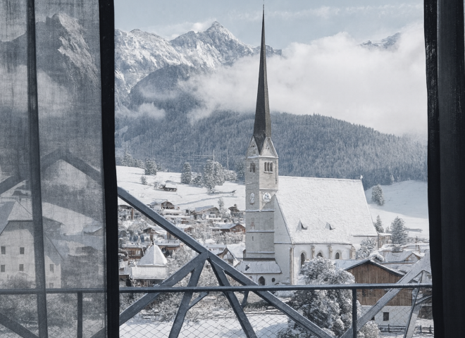 View from Hotel die HOCHKÖNIGIN room overlooking the snowy church of Maria Alm and the majestic Hochkönig peaks.