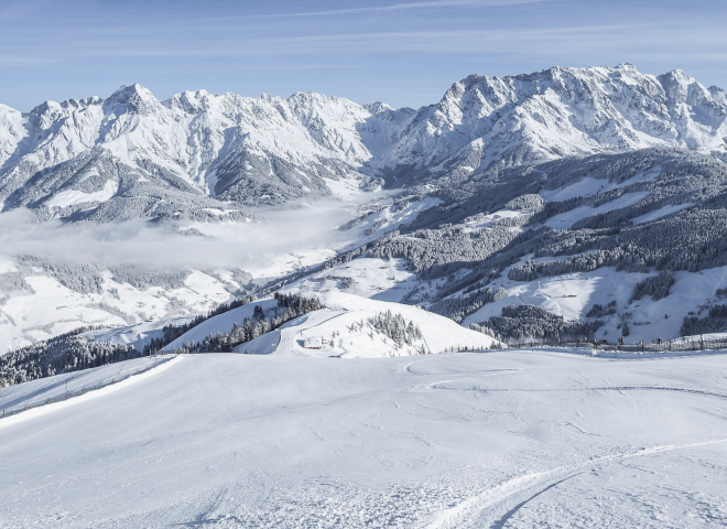 Winter panorama on the Hochkönig overlooking the Maria Alm ski area – snow-covered slopes, bright sunshine and the majestic peaks of the Alps make this winter holiday in Salzburg unforgettable.