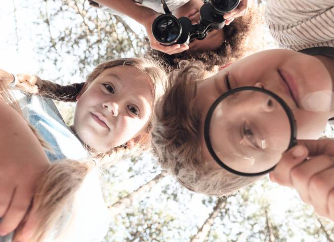 Kinder erkunden neugierig die Natur mit Lupe und Fernglas – ein Moment voller Entdeckerfreude beim Familienurlaub in der Hochkönig-Region rund um Maria Alm.