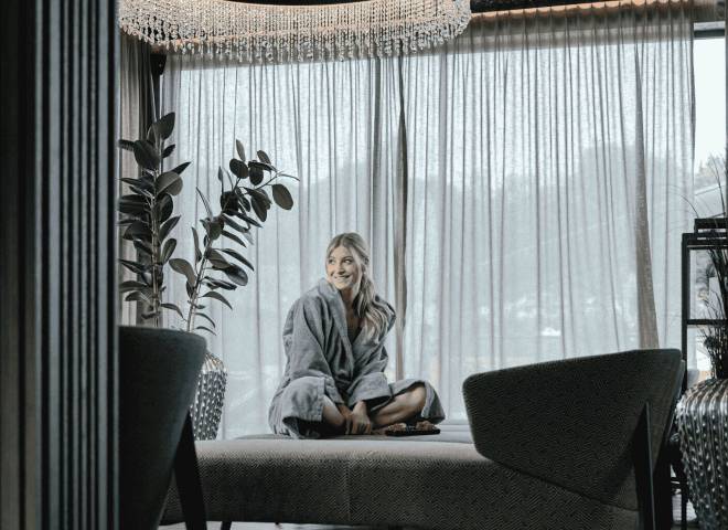 Frau im Bademantel entspannt im stilvollen Ruhebereich des Spas im Hotel die HOCHKÖNIGIN in Maria Alm am Hochkönig.