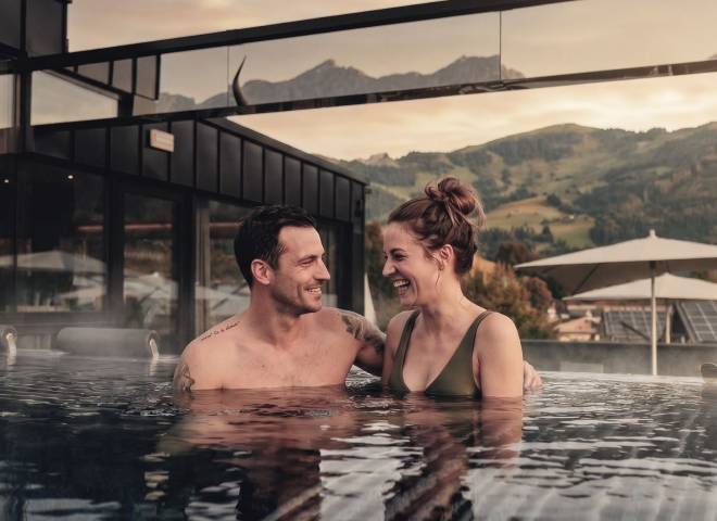 Paar entspannt im Infinitypool des TIARA SPA Adults Only Bereichs mit Bergblick im Wellnesshotel die HOCHKÖNIGIN in Maria Alm am Hochkönig.