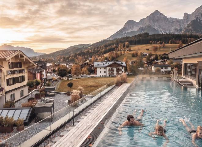 Familie entspannt im beheizten Außenpool der HOCHKÖNIGIN mit Blick auf das Hochkönig-Massiv in Maria Alm.