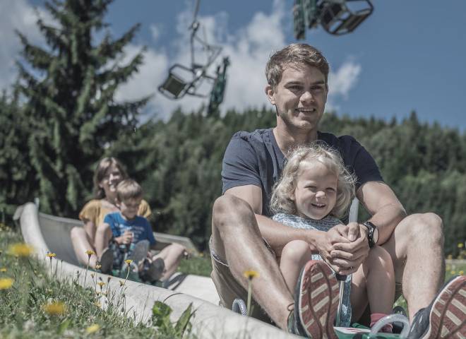 Familie beim Rutschen im Waldrutschenpark am Prinzenberg Natrun in Maria Alm