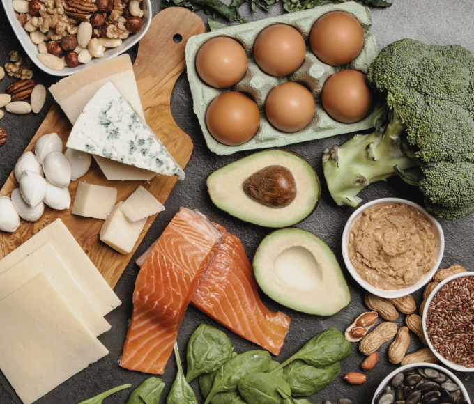 verschiedene Gemüsesorten, Fisch, Eier, Nüsse, Käse, Samen und Kräuter auf einem Tisch angerichtet