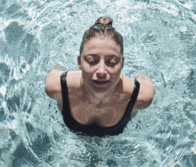 Frau mit geschlossenen Augen beim auftauchen im Pool