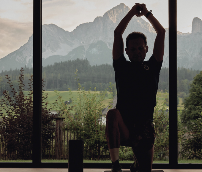 Mann beim Yoga mit abendlicher Stimmung und die Berge im Hintergrund