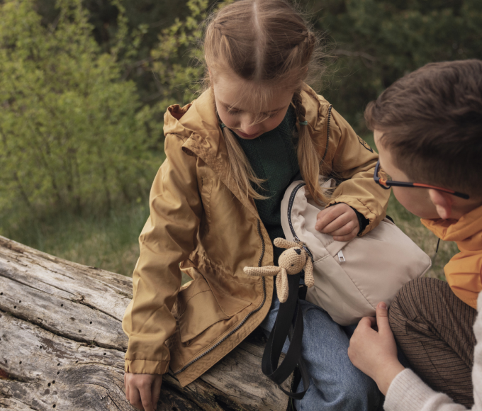 Two children sitting on a tree trunk in the forest near Maria Alm, Salzburg Alps – peaceful family moment at Hotel die HOCHKÖNIGIN in the Hochkönig region