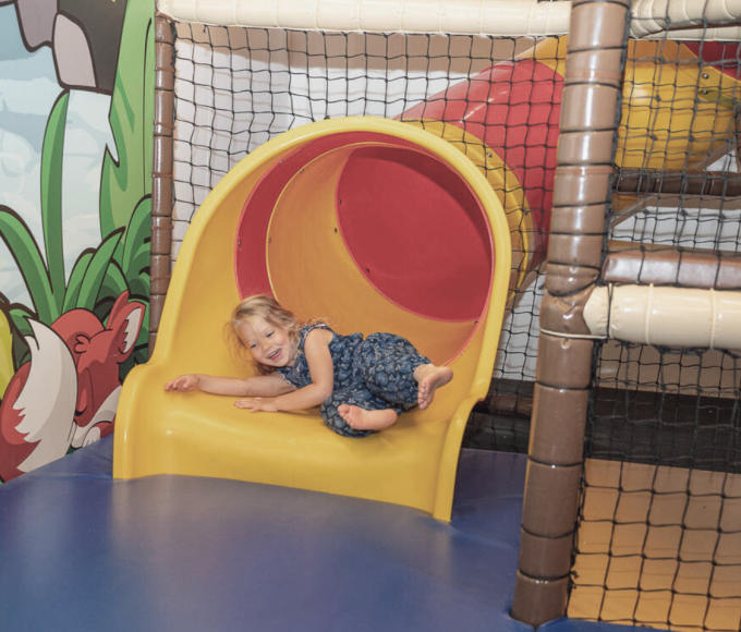 Child sliding through the colorful tube slide in the FUN ARENA at Hotel die HOCHKÖNIGIN, Maria Alm – indoor playground fun in the Salzburg Alps