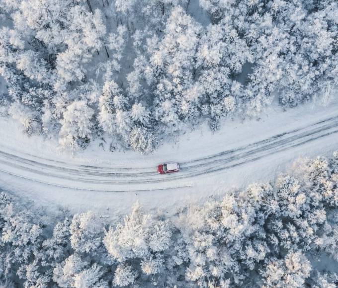 Winterliche Luftaufnahme einer verschneiten Straße durch dichten Winterwald bei Maria Alm am Hochkönig im Salzburger Land – idyllische Anreise im Winterurlaub, alpine Natur, Schnee, Ruhe und Berglandschaft in Österreich