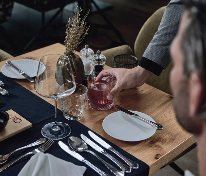 Elegant fine dining table with drink service at the gourmet restaurant of Hotel die HOCHKÖNIGIN in Maria Alm, Austria, showcasing refined alpine cuisine and atmosphere.