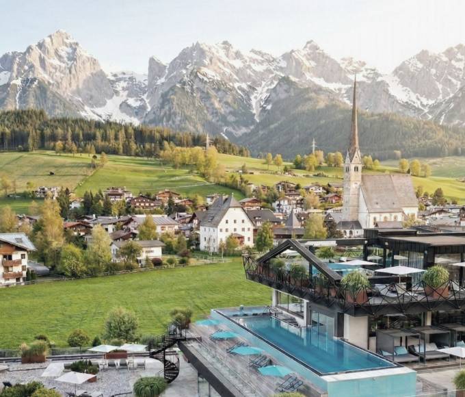 Infinitypool im TIARA SPA des Wellnesshotels die HOCHKÖNIGIN in Maria Alm mit Blick auf die Kirche und das Hochkönig-Gebirge.