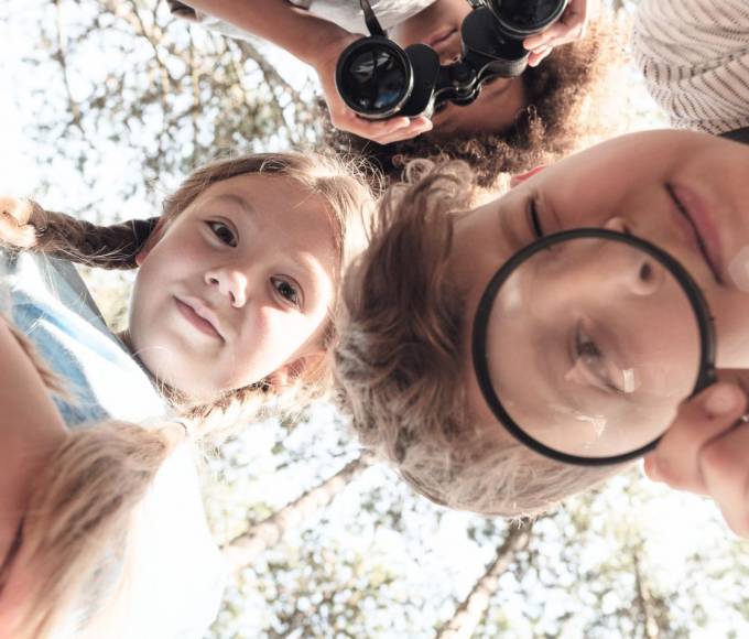 Children exploring nature with a magnifying glass and binoculars – a joyful discovery moment during a family holiday in the Hochkönig region near Maria Alm.