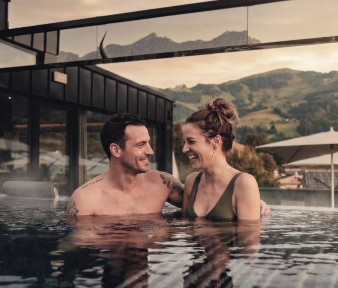 Paar entspannt im Infinitypool des TIARA SPA Adults Only Bereichs mit Bergblick im Wellnesshotel die HOCHKÖNIGIN in Maria Alm am Hochkönig.