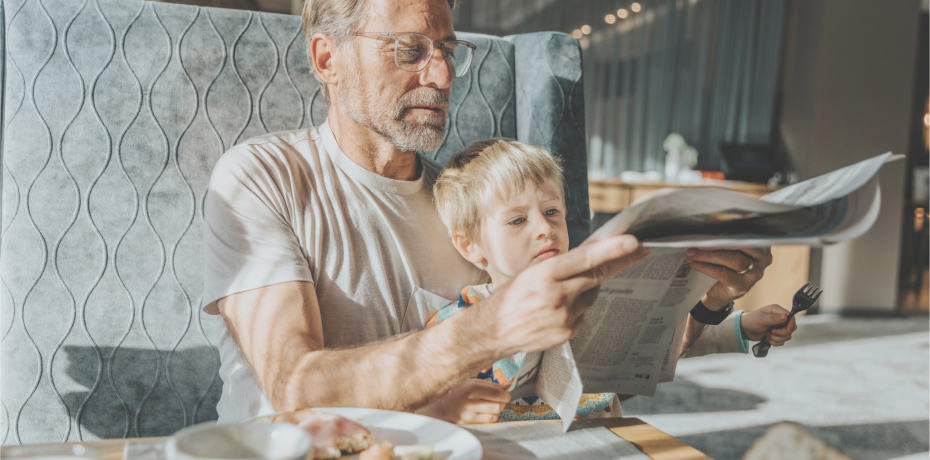 Father and son having breakfast in the hotel restaurant with a newspaper