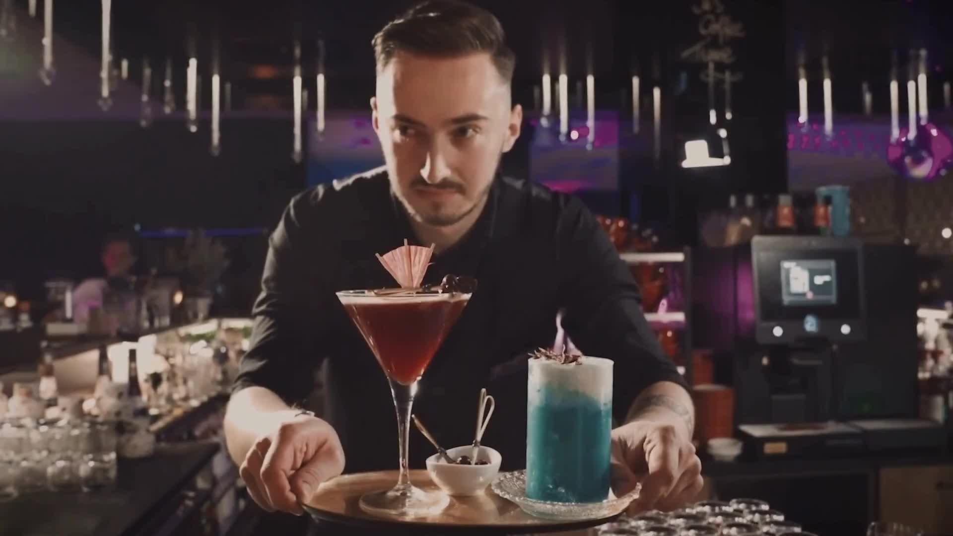 Cocktail an der Bar mit Barkeeper und Dame die den Cocktail trinkt