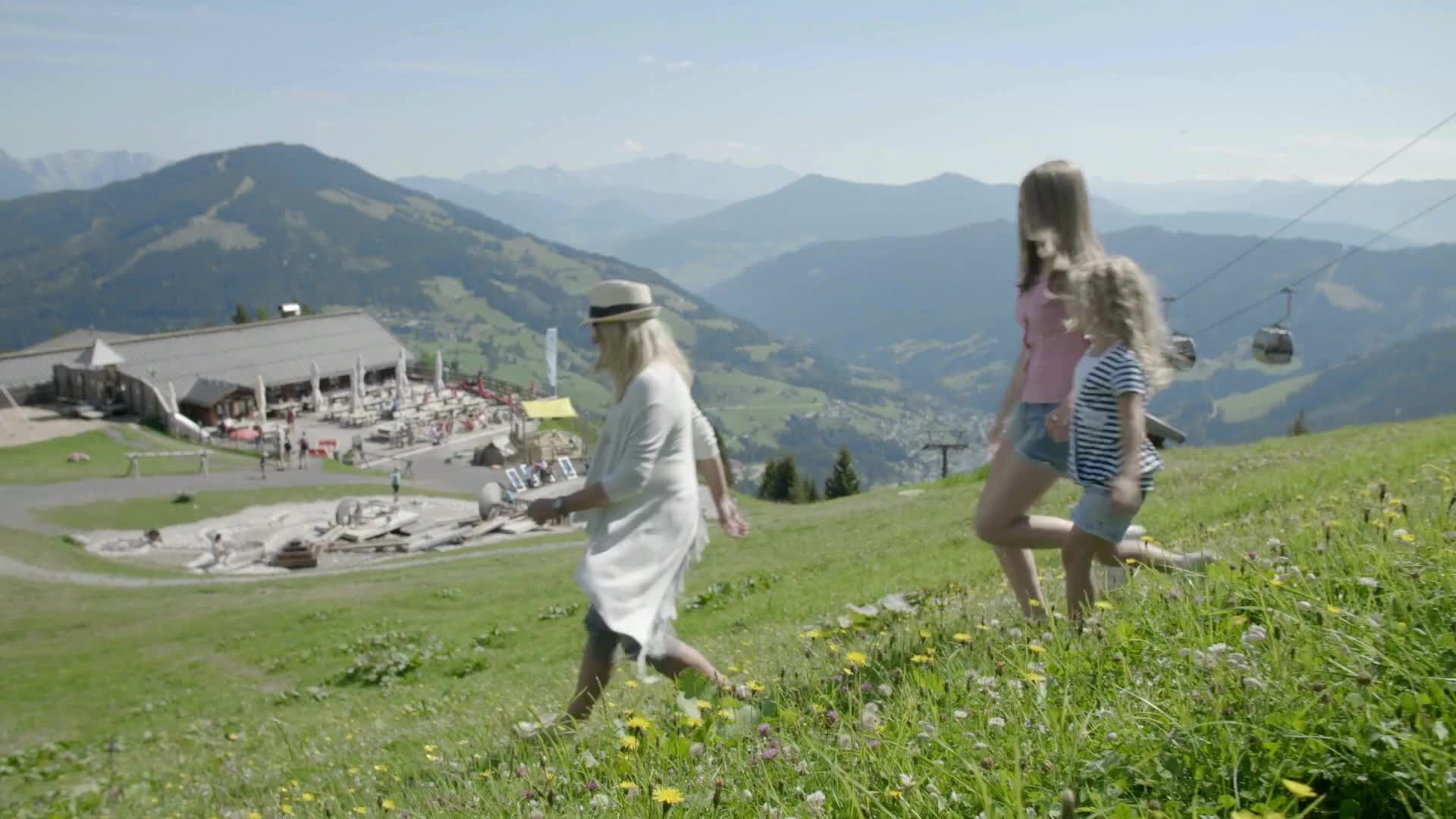 Familie im Sommer in den Bergen beim laufen über Almen und Spielen am Almspielplatz