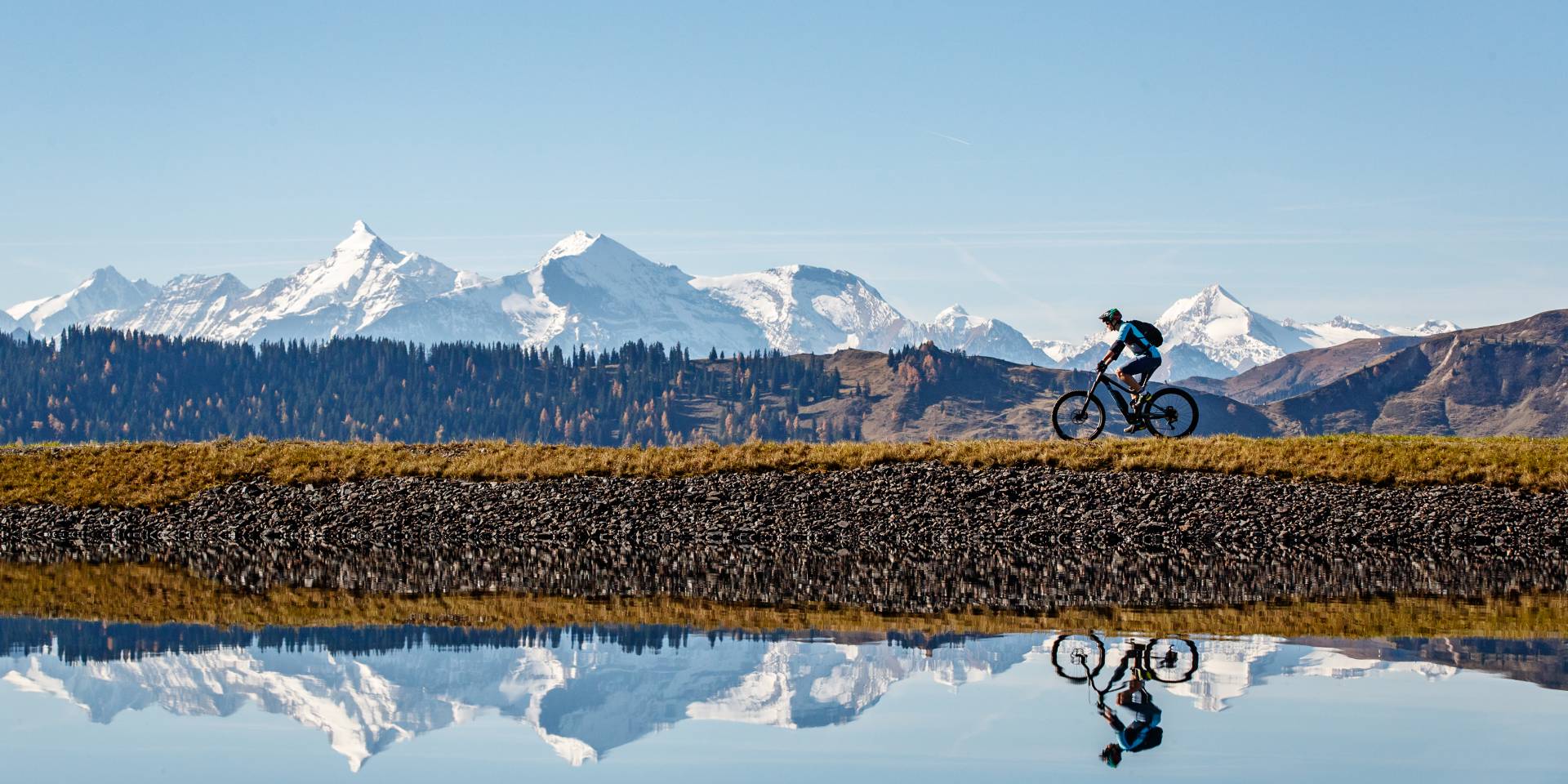 Radfahrer spiegelt sich im See mit Berglandschaft