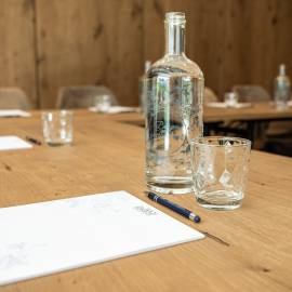 Glasflasche mit Bergquellwasser steht auf Tagungstisch