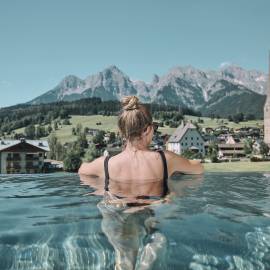 Woman in the infinity pool with a fantastic view of the surrounding mountains