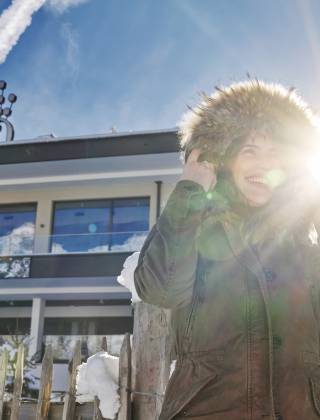 Frau in Winterjacke steht vor dem Wellnesshotel die Hochkönigin in Österreich