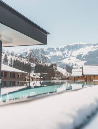 Infinity Pool mit Aussicht auf die schneebedeckten Berge in der HOCHKÖNIGIN in Maria Alm