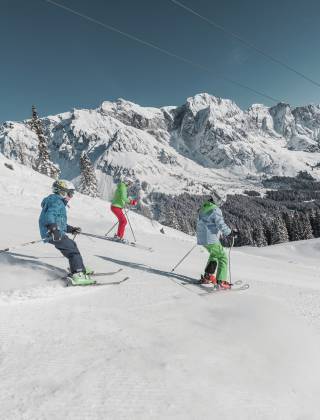Familie beim Ski fahren in der verschneiten Winterlandschaft in den Bergen im Salzburger Land