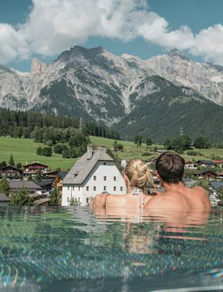 Paar im Whirlpool mit fantastischem Blick auf die Berge