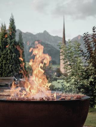 Fire bowl with a view from the terrace of the HOCHKÖNIGIN of the church of Maria Alm and the surrounding mountain world