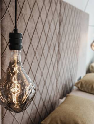 Partial view of the room in the HOCHKÖNIGIN with stylish wallpaper, lamp and bed