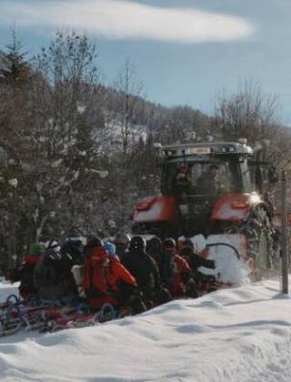 People being pulled up the mountain by a tractot with a sledge in winter