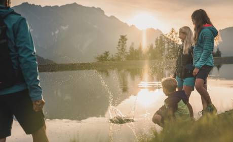 Familie wirft Stein in den Bergsee am Hochkönig