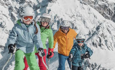 Familie im Schnee in den Bergen beim Skifahren